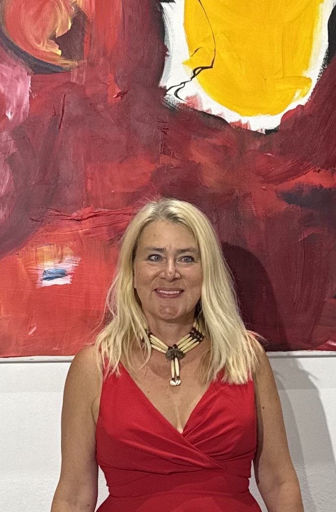 Susanne Rikus im roten Kleid vor ihrem Gemälde in Rot und Gelb
